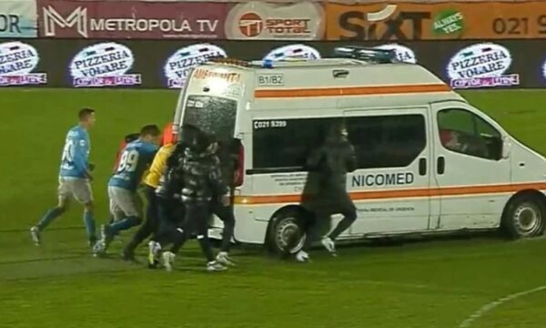 Futbollistët shtyjnë autoambulancën e bllokuar në baltë gjatë ndeshjes